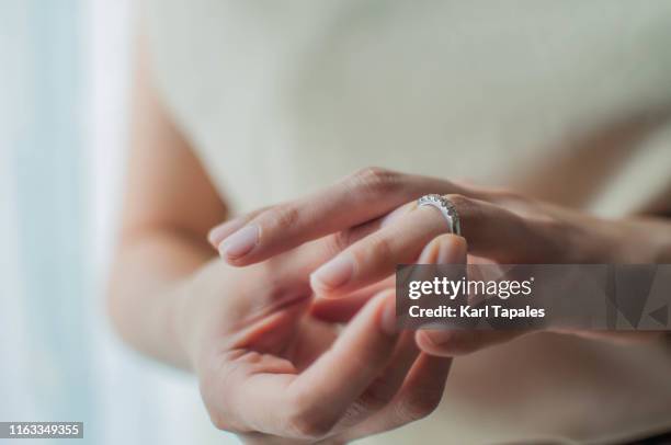 a young woman is wearing her wedding ring - taking off wedding ring stock pictures, royalty-free photos & images