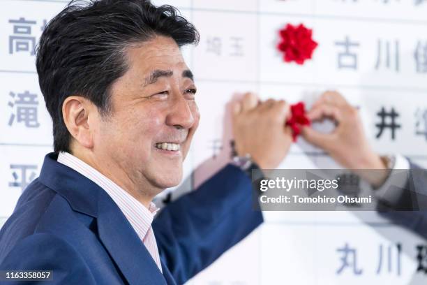 Japan's Prime Minister and ruling Liberal Democratic Party President Shinzo Abe places a red paper rose on a LDP candidate's name to indicate an...