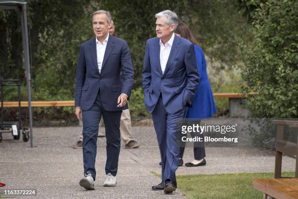 Mark Carney, governor of the Bank of England , left, and Jerome Powell, chairman of the U.S. Federal Reserve, walk the grounds during the Jackson...