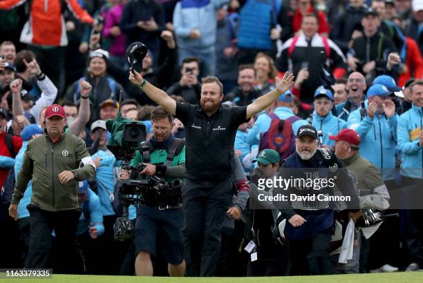 Shane Lowry of Ireland breaks through the huge crowds on the 18th hole and celebrates with his caddie Brian Martin on his way to completing his...