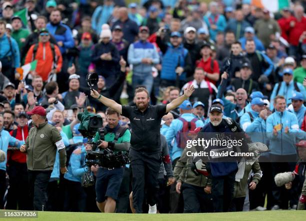 Shane Lowry of Ireland breaks through the huge crowds on the 18th hole and celebrates with his caddie Brian Martin on his way to completing his...