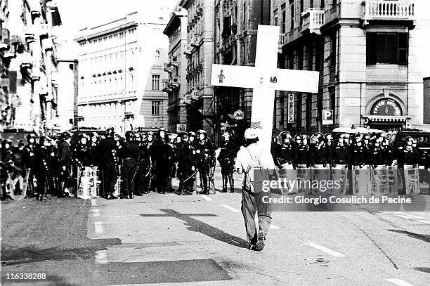Protester holds a cross as he face's the police during a protest against the 27th G8 Summit In Genoa, on July 21, 2001 in Genoa, Italy. Hundreds of...