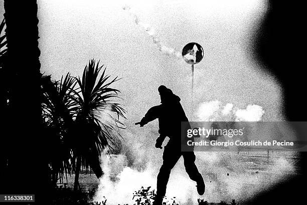 An anti-globalisation activist throws back a tear gas grenade at police during a protest against the 27th G8 Summit In Genoa, on July 21, 2001 in...