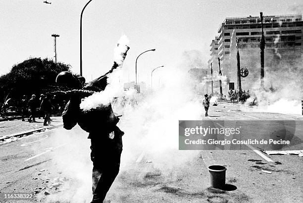 An anti-globalisation activist throws back a tear gas grenade at police during a protest against the 27th G8 Summit In Genoa, on July 21, 2001 in...
