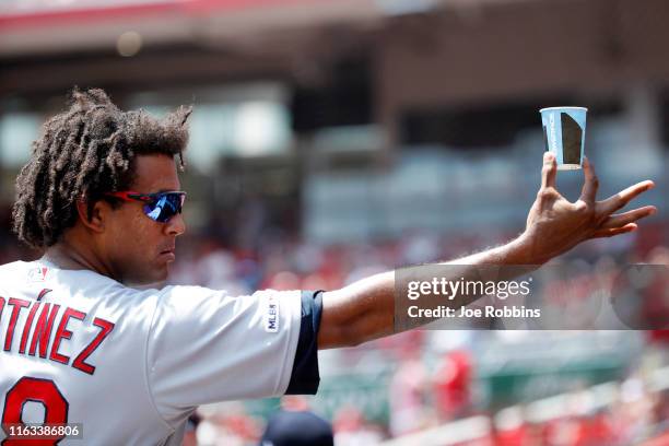 Jose Martinez of the St. Louis Cardinals holds out a cup of water toward fans while looking on in the dugout in the third inning against the...