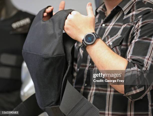 In this photo illustration, Garrett Casutt, Purchasing Manager for Citizen Armor, holds a bulletproof vests that is made specifically for woman on...