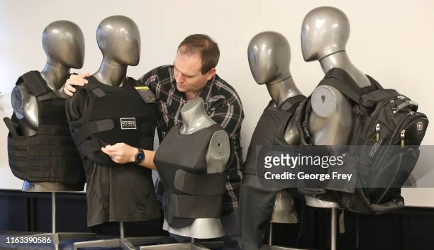 In this photo illustration, Garrett Casutt, Purchasing Manager for Citizen Armor, adjusts one of their T-shield ultra concealed bulletproof vests as...