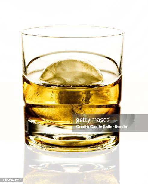 glass of scotch with a round ice ball on white background - glass ice stock-fotos und bilder