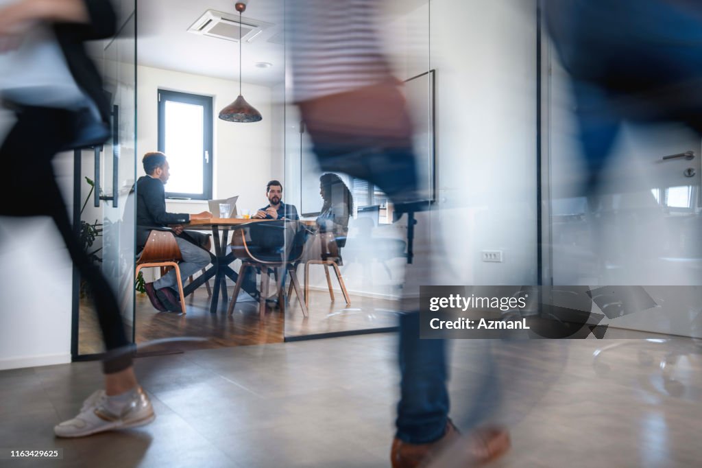 Zakenlui in vergaderzaal en collega's wandelen door