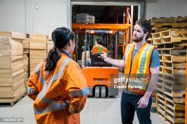 un tema de seguridad en el lugar de trabajo de almacén industrial. un gerente discute un problema sobre un conductor de carretilla elevadora. - disturbios fotografías e imágenes de stock