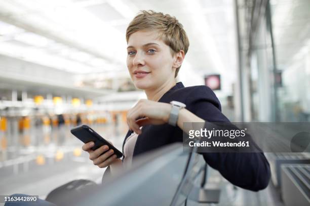 portrait of blond businesswoman using smartphone - airport smartphone stock-fotos und bilder