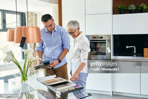 man and mature woman in a kitchen retail store examining material samples - sales assistant furniture stock pictures, royalty-free photos & images