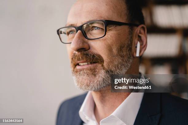 portrait of mature businessman listening to music with bluetooth earbuds - bluetooth headphones stock pictures, royalty-free photos & images