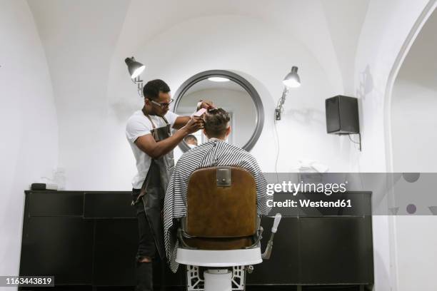 barber cutting hair of a customer in barber shop - schürze mann rückansicht stock-fotos und bilder