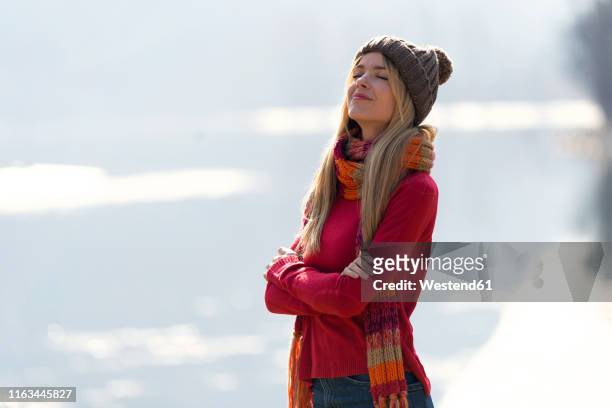 young blond woman at a lake in winter - sweater weather stock pictures, royalty-free photos & images
