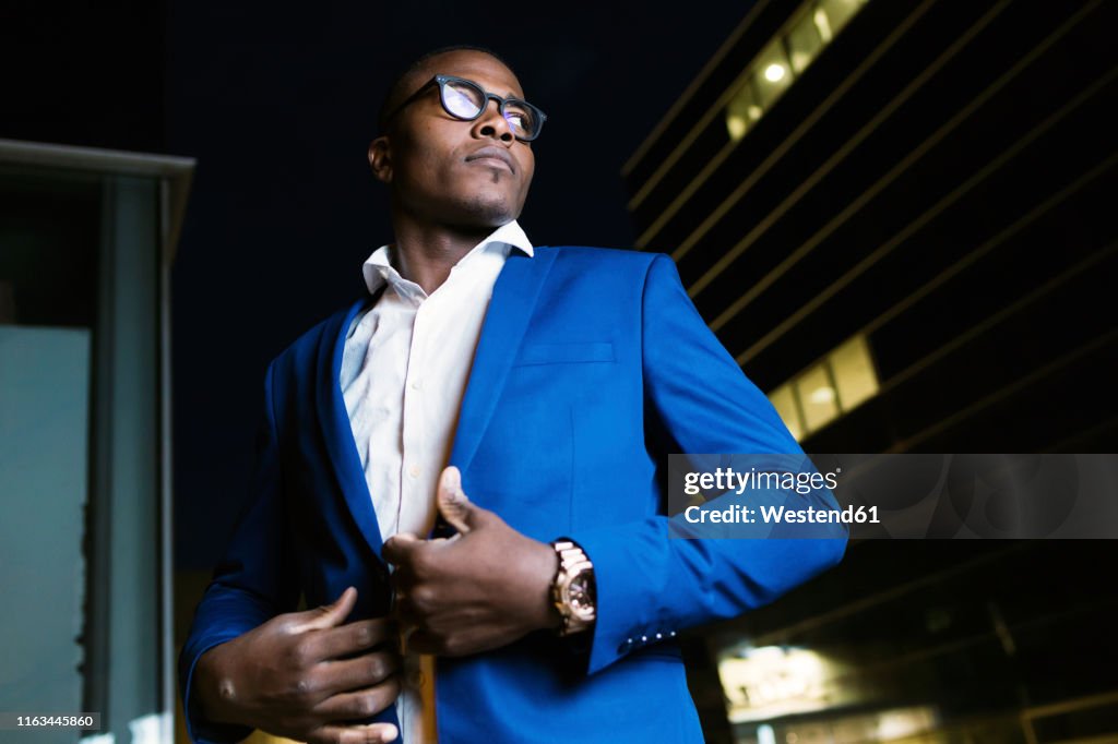 Young businessman wearing blue suit jacket, ooking sideways at night