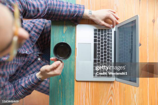 man wearing pyjama sitting with coffee cup in front of laptop - pyjamas stock pictures, royalty-free photos & images