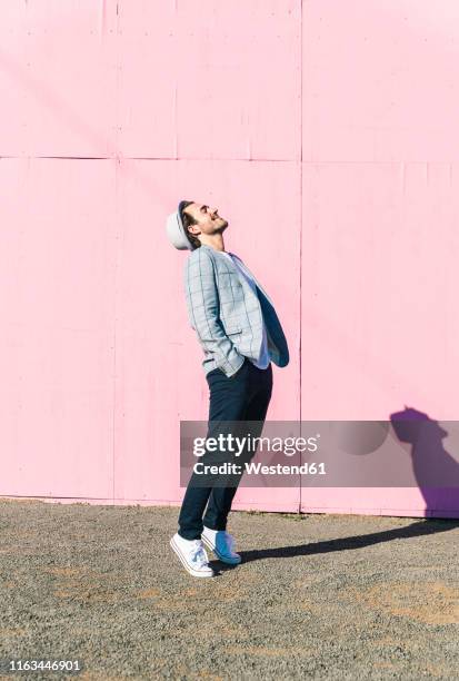 happy young man in front of pink construction barrier, standing on tiptoes, smiling - hat and suit stock pictures, royalty-free photos & images