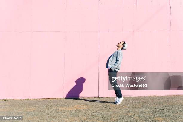 happy young man in front of pink construction barrier, standing on tiptoes, smiling - tiptoe imagens e fotografias de stock