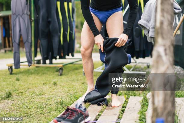 close-up of man preparing for a boat trip putting on wetsuit - black slip stock-fotos und bilder