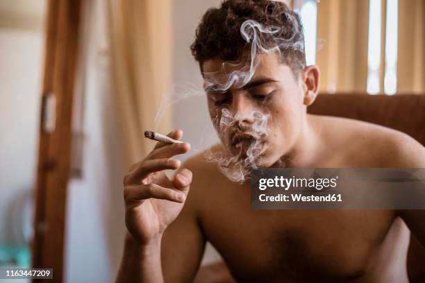 barechested man smoking a joint of marijuana - marijuana joint imagens e fotografias de stock