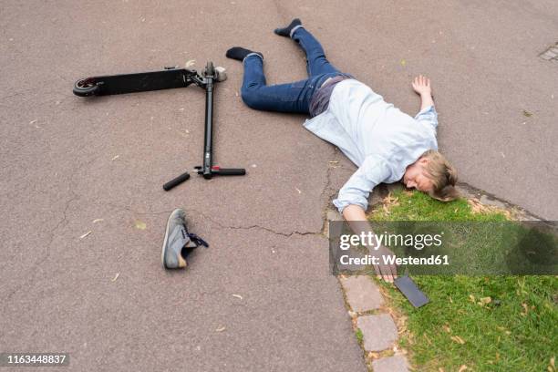 accident victim lying on road besides e-scooter and smartphone - broken phone stock-fotos und bilder