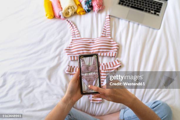 woman taking smartphone picture of bikini on bed - kleidungsstück stock-fotos und bilder