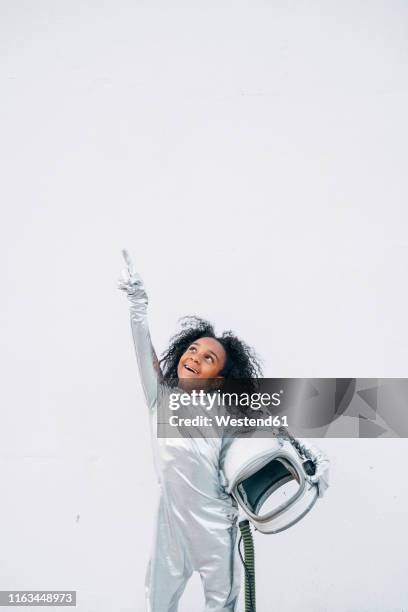 portrait of smiling little girl wearing space suit in front of white background looking up - astronaut kid stockfoto's en -beelden