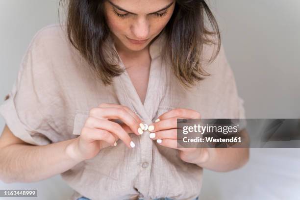 young woman buttoning her shirt - abrochar fotografías e imágenes de stock