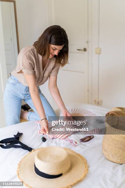 young woman placing bikini on bed - spread joy stock pictures, royalty-free photos & images