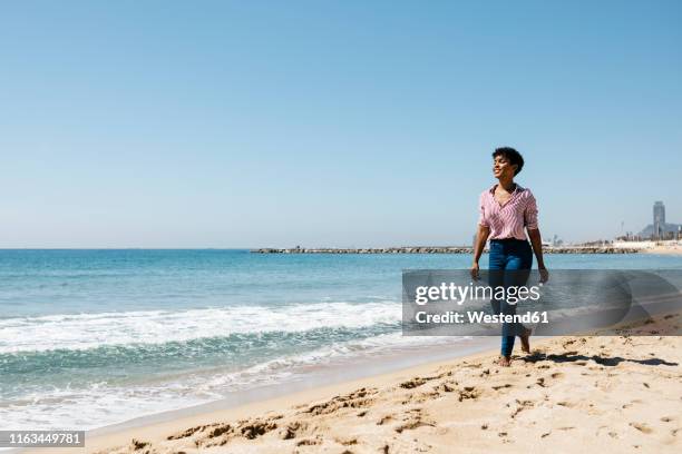woman walking on the beach, enjoying the sun after work - beach club stock pictures, royalty-free photos & images