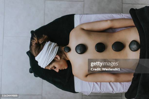 young woman with heated stones on her back - spa treatment stock pictures, royalty-free photos & images