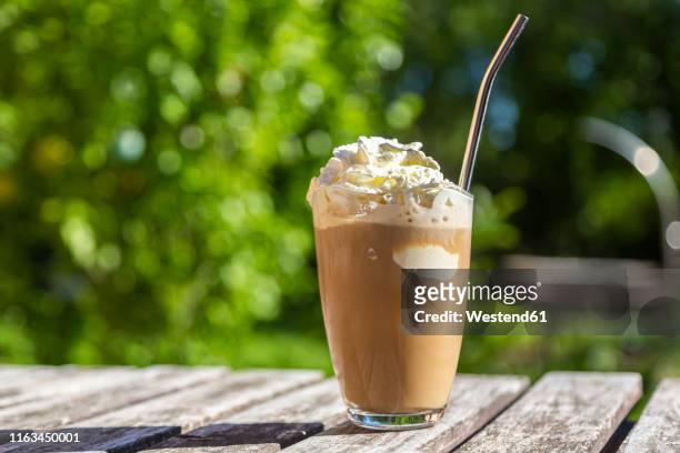 glass of iced coffee with cream topping on garden table - aufschäumen stock-fotos und bilder