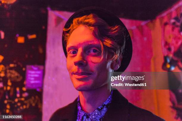 young man wearing hat during psychedelic party, effects of light machine on a wall - crazy party stockfoto's en -beelden