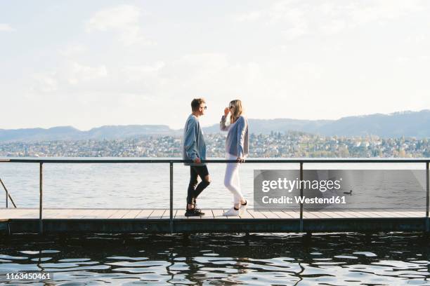 young couple standing on jetty at lake zurich, zurich, switzerland - jetty stock pictures, royalty-free photos & images