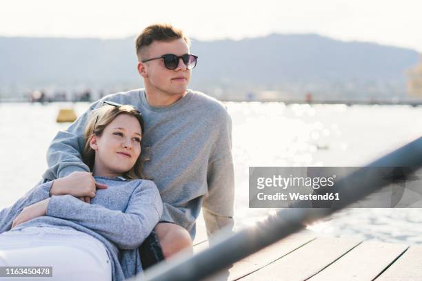 young couple relaxing on jetty at lake zurich, zurich, switzerland - lake zurich switzerland stock pictures, royalty-free photos & images