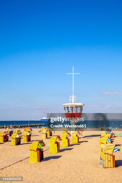 view to beach with hooded beach chairs and attendant's tower, luebeck travemuende, germany - travemuende stock pictures, royalty-free photos & images