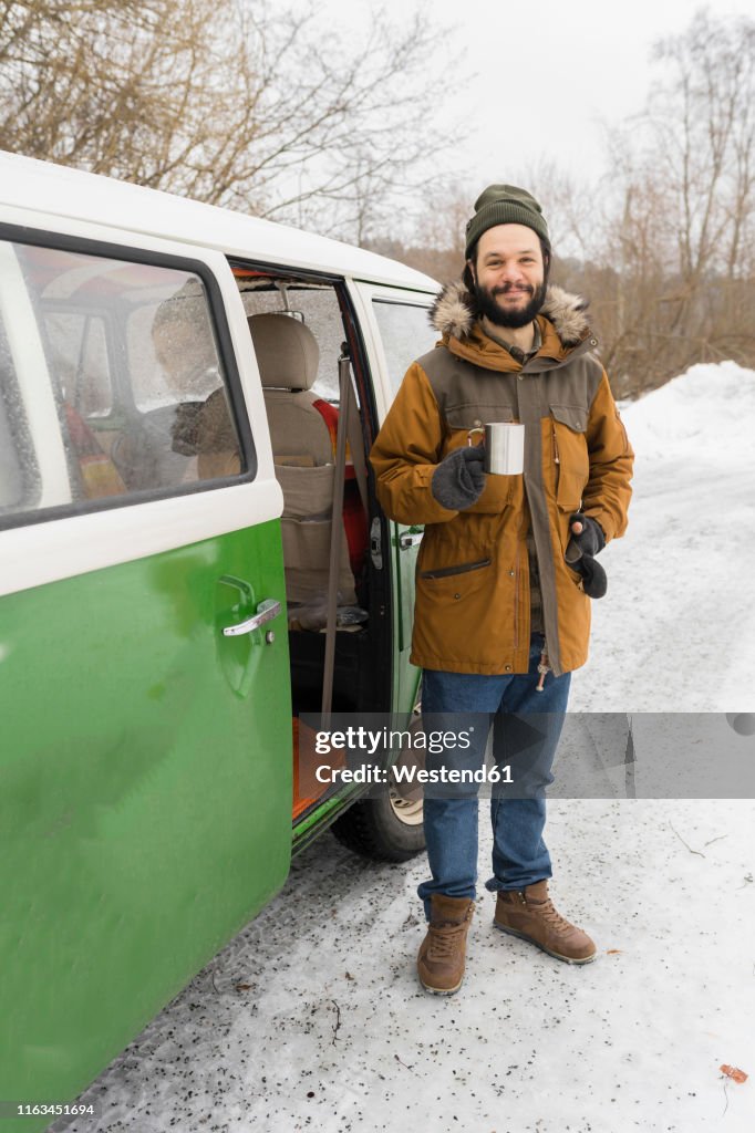 Portrait of smiling man with electric van in winter landscape, Kuopio, Finland
