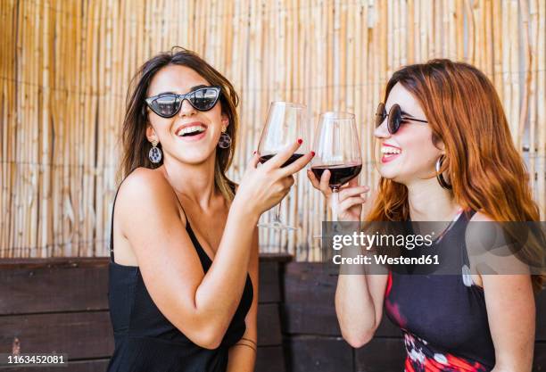 two happy women having a glass of red wine at a bar - brown hair drink wine stock pictures, royalty-free photos & images