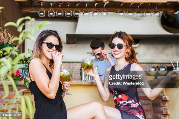 two women having a drink at a bar - cocktail sommer stockfoto's en -beelden