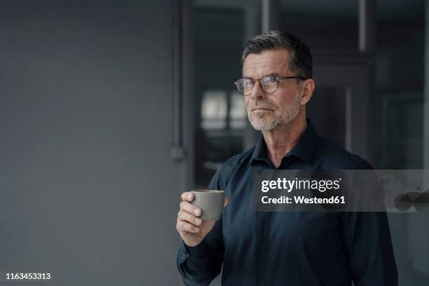 portrait of mature businessman holding a cup - smart glass stock-fotos und bilder