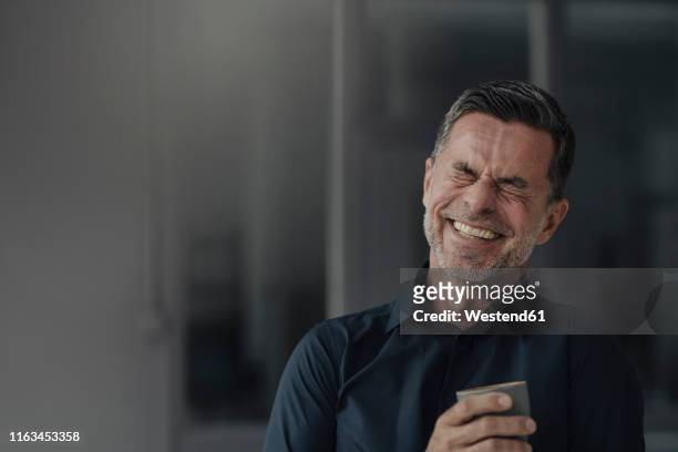 happy mature businessman holding a cup - lachen stock-fotos und bilder