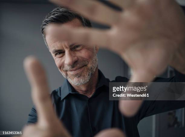 portrait of smiling mature businessman making a finger frame - esprimere a gesti foto e immagini stock