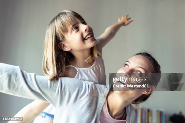 mother and daughter playing at home, pretending to fly - huckepack nehmen stock-fotos und bilder