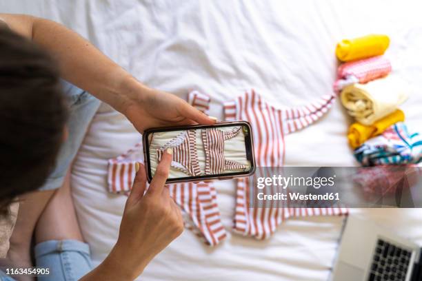 woman taking smartphone picture of bikini on bed - roll call stock pictures, royalty-free photos & images