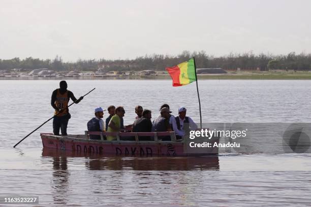 Man uses a pole to steer a boat carrying tourists at Lac Rose near Dakar, Senegal on August 23, 2019. The Pink Lake is known to the local salt...