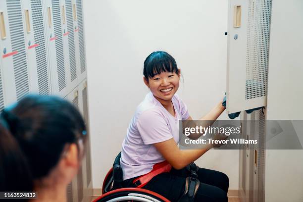Two teenage girls in talking in a locker room after playing wheelchair tennis