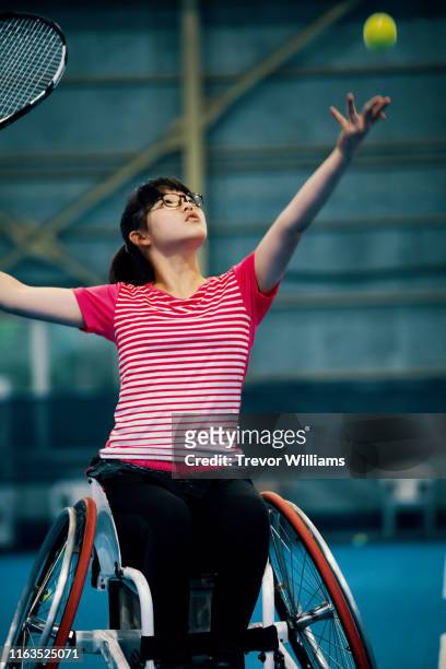 teenage girl playing a wheelchair tennis match at an indoor tennis court - wheelchair tennis stock pictures, royalty-free photos & images