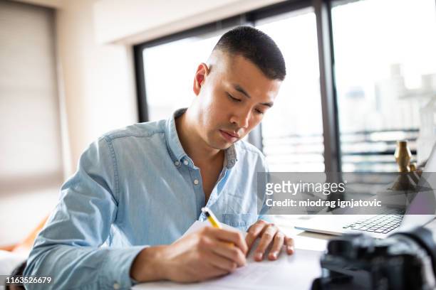 good-looking chinese man signing paper documents - journalist laptop stock pictures, royalty-free photos & images