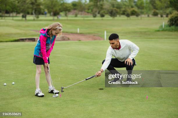 coaching a young girl golfing - golf lessons stock pictures, royalty-free photos & images